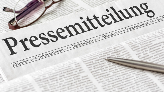 Zeitung mit der Überschrift Pressemitteilung Zeitung mit der Überschrift Pressemitteilung mit brille und kuli