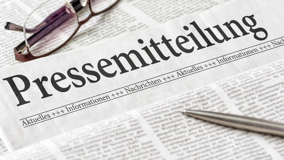 Zeitung mit der Überschrift Pressemitteilung Zeitung mit der Überschrift Pressemitteilung mit Brille und Kuli