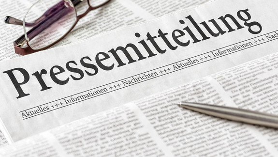 Zeitung mit der Überschrift Pressemitteilung Zeitung mit der Überschrift Pressemitteilung mit Brille und Kuli