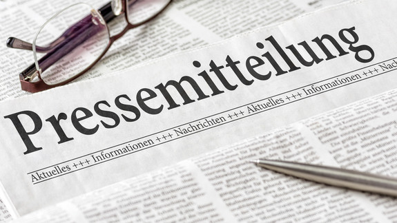 Zeitung mit der Überschrift Pressemitteilung Zeitung mit der Überschrift Pressemitteilung mit Brille und Kuli