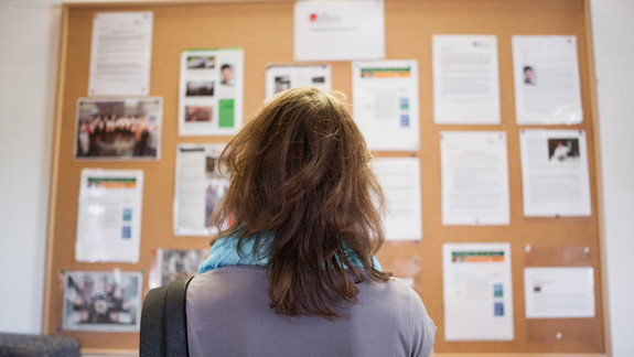 Aushang Forderungen Tarifrunde 2023 Frau steht vor Aushängen und liest